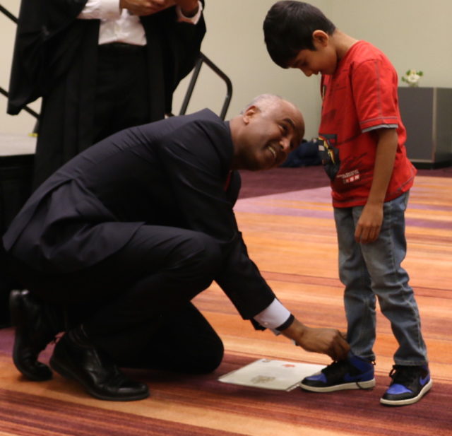 Immigration Minister Hussen helps new Canadian tie shoelace